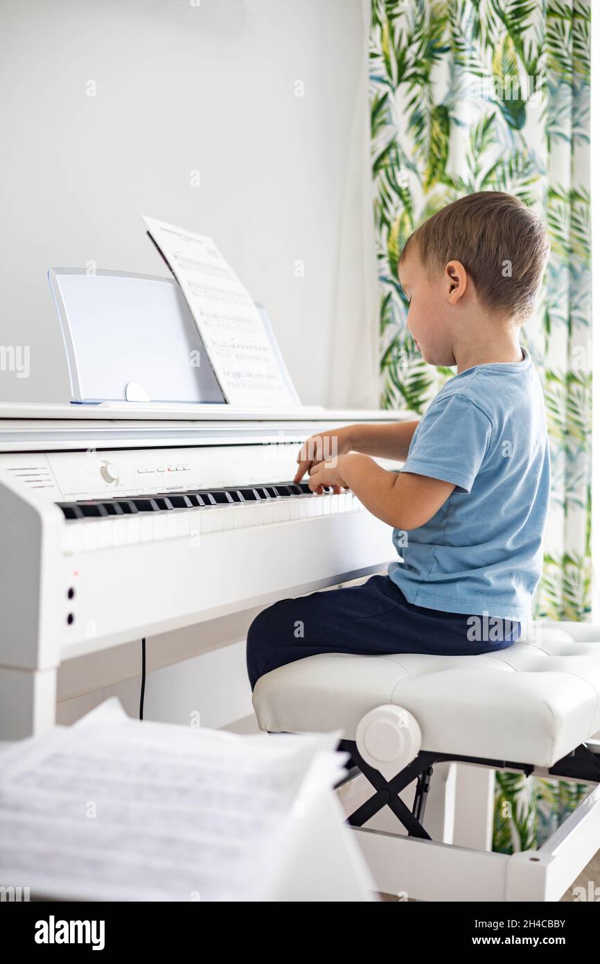 Lindo bebé niño tocando blanco eléctrico forte piano Teclas de presión niño  estudiando en la escuela musical Fotografía de stock - Alamy