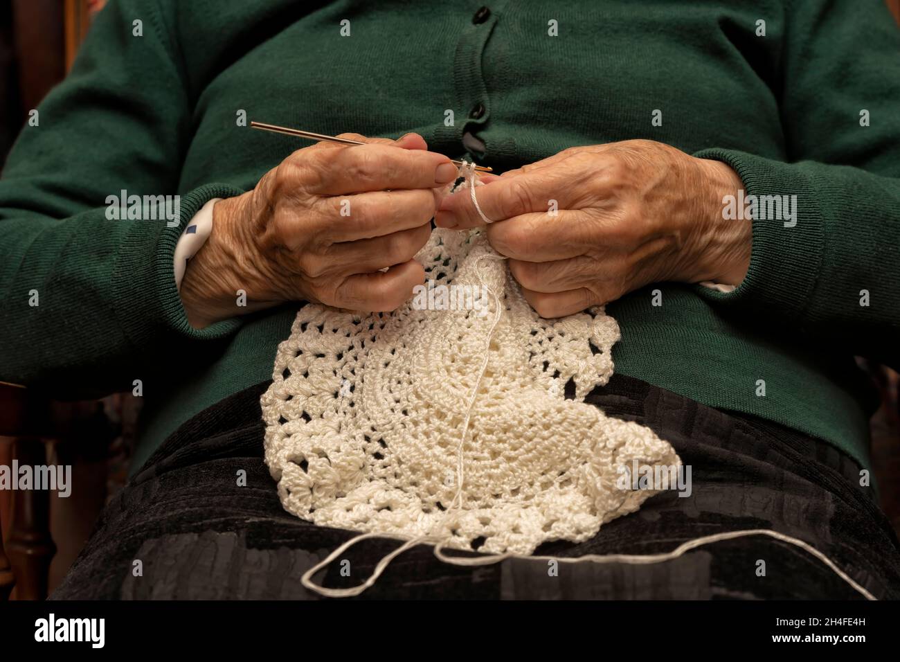 Una mujer de 90 años de edad crochets con hilo blanco en casa Foto de stock