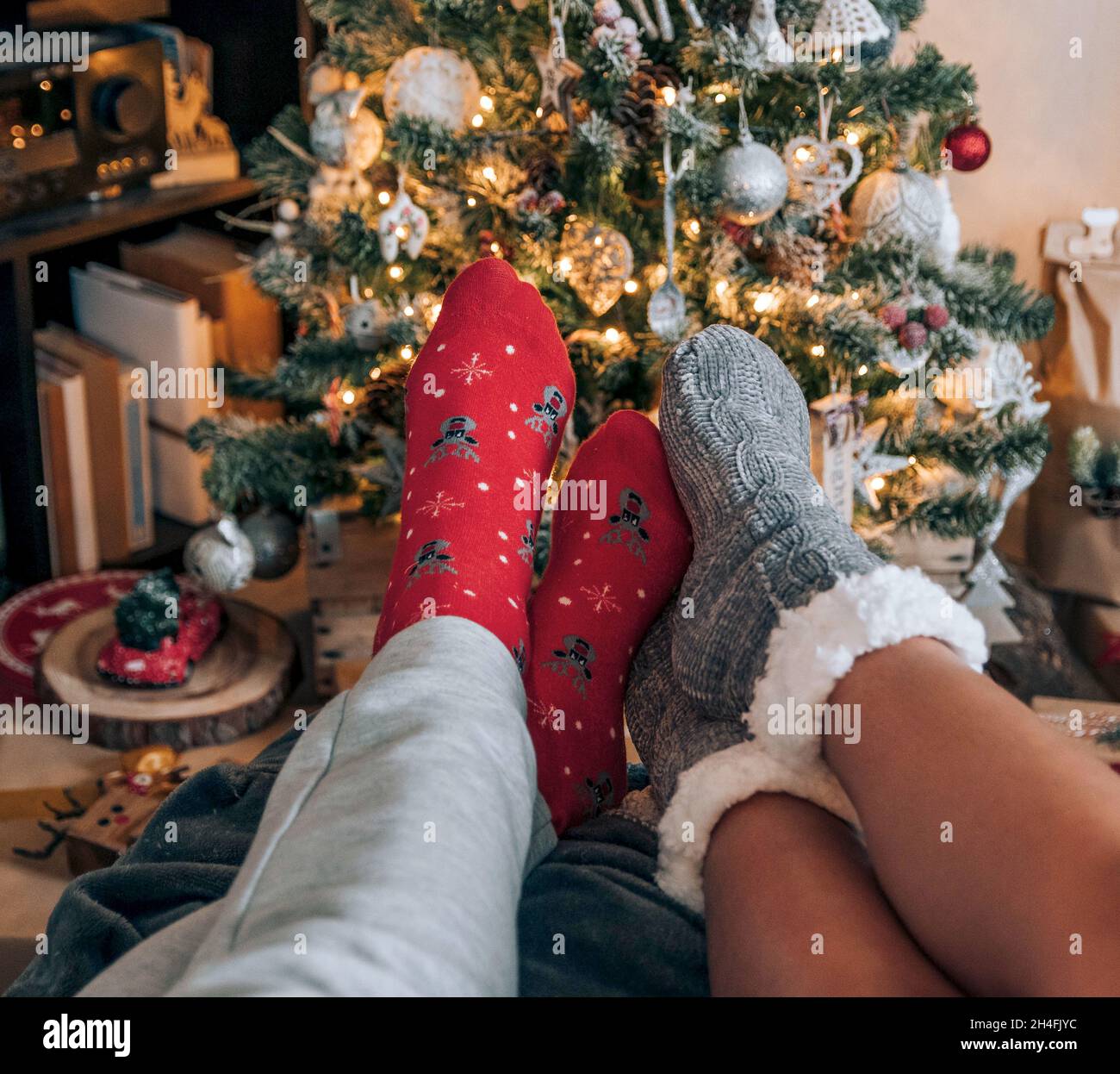 Perspectiva personal de la pareja con calcetines cómodos delante del árbol de Navidad decorado. Foto de stock