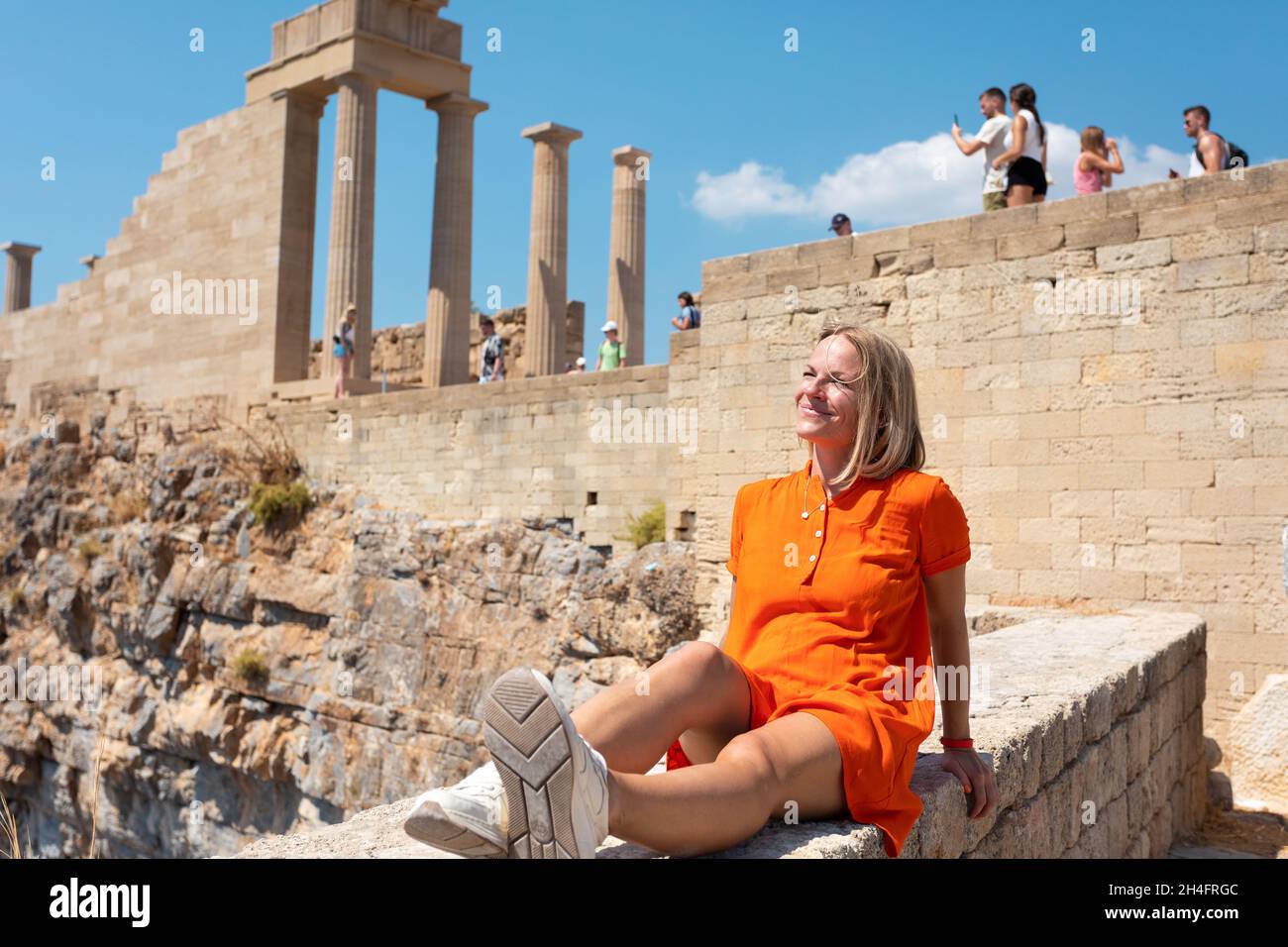 Black Hipster viajero sonriendo sentado en ruinas, en el fondo del Partenón en la Acrópolis de Atenas, Grecia. Mujer de vacaciones disfrutando del Foto de stock