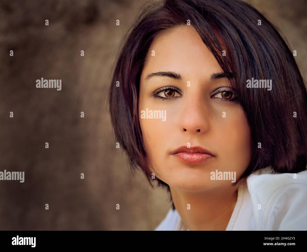Mujer caucásica en sus últimos 20 años con el pelo corto oscuro mirando la cámara con una mirada fija en blanco Foto de stock
