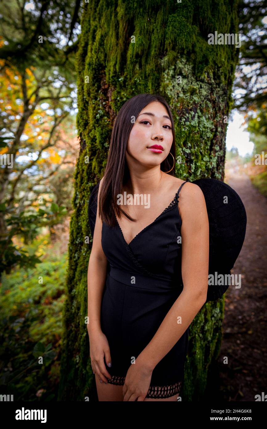 Mujer joven con un conjunto de cosplay de Grim Reaper en el bosque Foto de stock