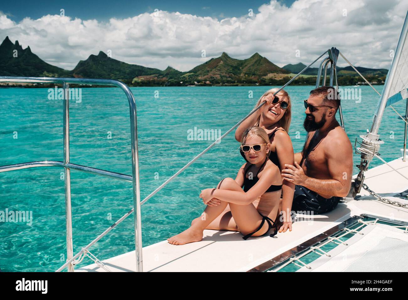 Una familia feliz en trajes de baño se sienta en un catamarán en el océano  Índico. retrato de una familia en un yate en el arrecife de coral de la  isla de