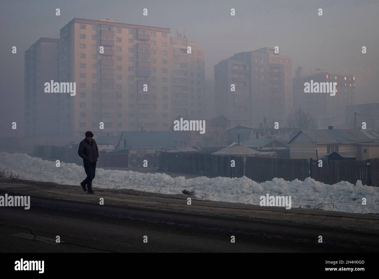 Un hombre camina por los bloques de apartamentos de la ciudad durante una mañana muy contaminada en Ulaanbaatar, Mongolia, 19 de enero de 2019. Durante el duro invierno mongol Foto de stock