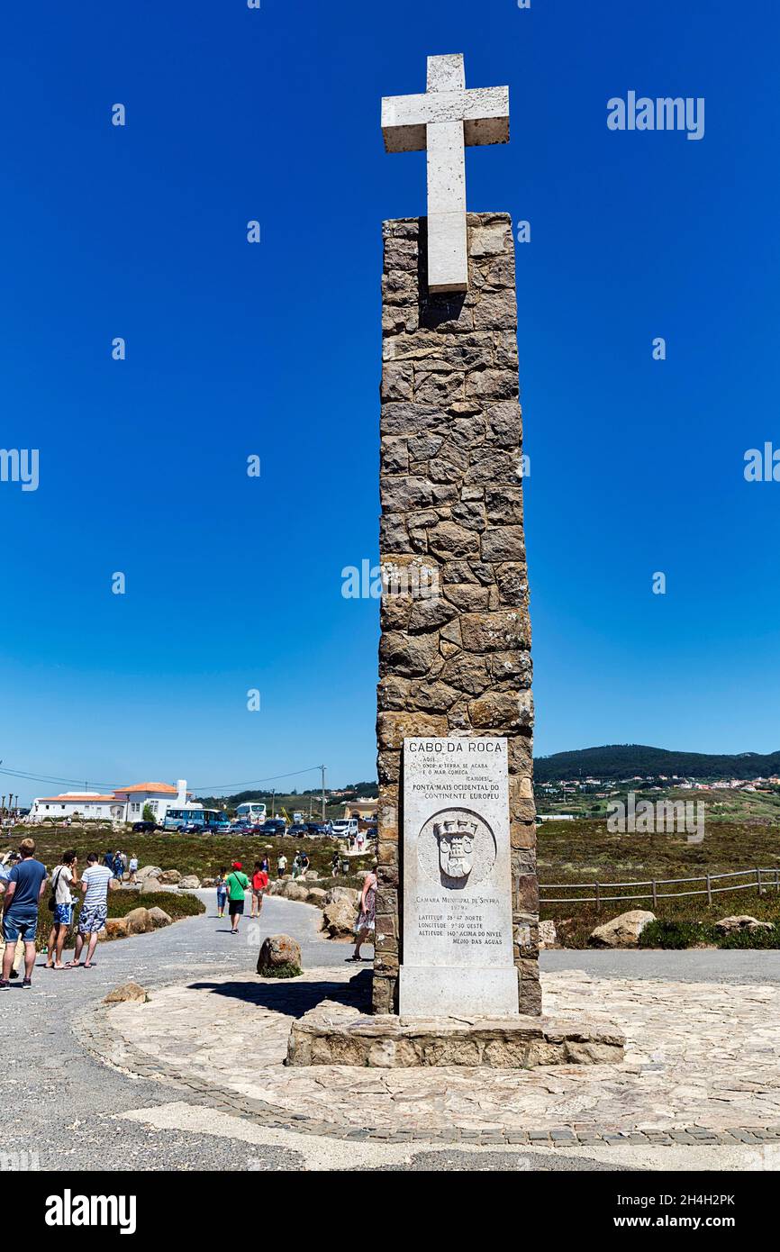 Turistas en el monumento con cruz de piedra y tablero de información, punto más occidental del continente de Europa, Cabo da Roca, Sintra, distrito de Lisboa Foto de stock