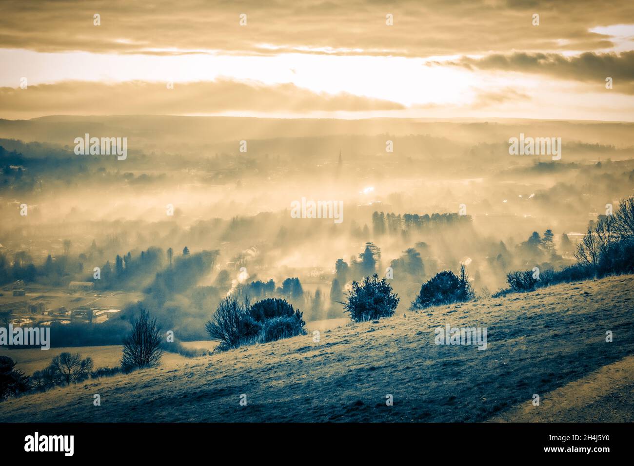 Paisaje de una puesta de sol de otoño con rayos de luz llamativos, mirando  a través de las colinas de Surrey desde Box Hill en un tono mono dividido,  31st de diciembre