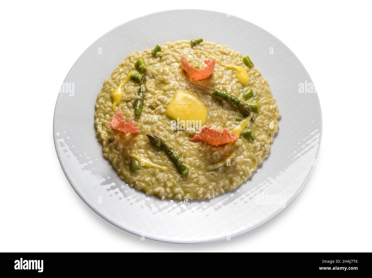 Risotto con espárragos en plato blanco aislado sobre fondo blanco, receta gourmet de arroz italiano Foto de stock