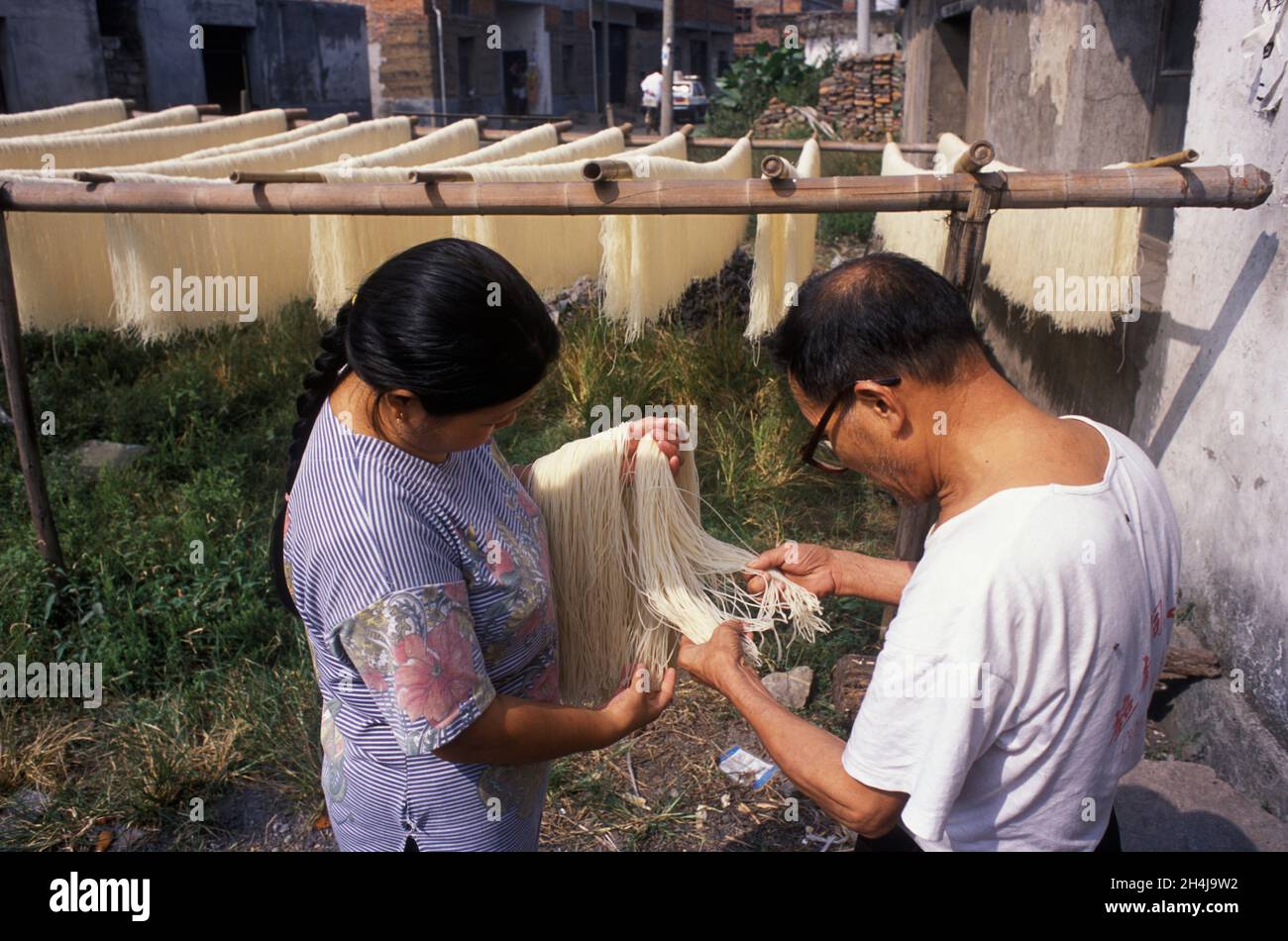 Fideos chinos 2000s.. Una pareja de mediana edad inspecciona la calidad de los fideos que han hecho para su tienda, que han sido colgados para secarse en los estantes. Yiwu, Provincia de Zhejiang, China 2001 HOMER SYKES Foto de stock