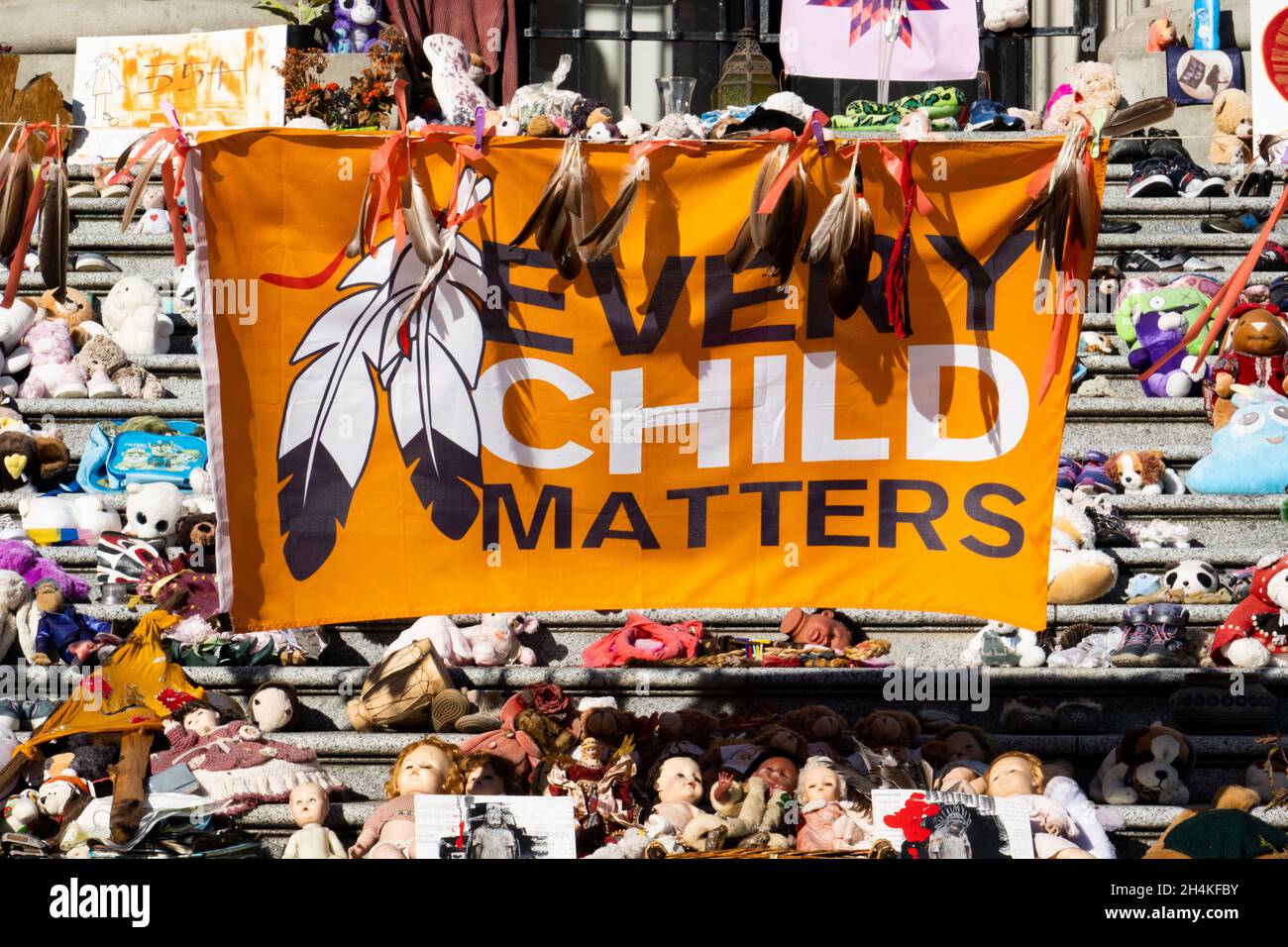 Zapatos, juguetes, flores son parte de un monumento conmemorativo y protesta sobre las víctimas infantiles de las escuelas residenciales indias en Canadá, en los pasos en el Vancouver Foto de stock