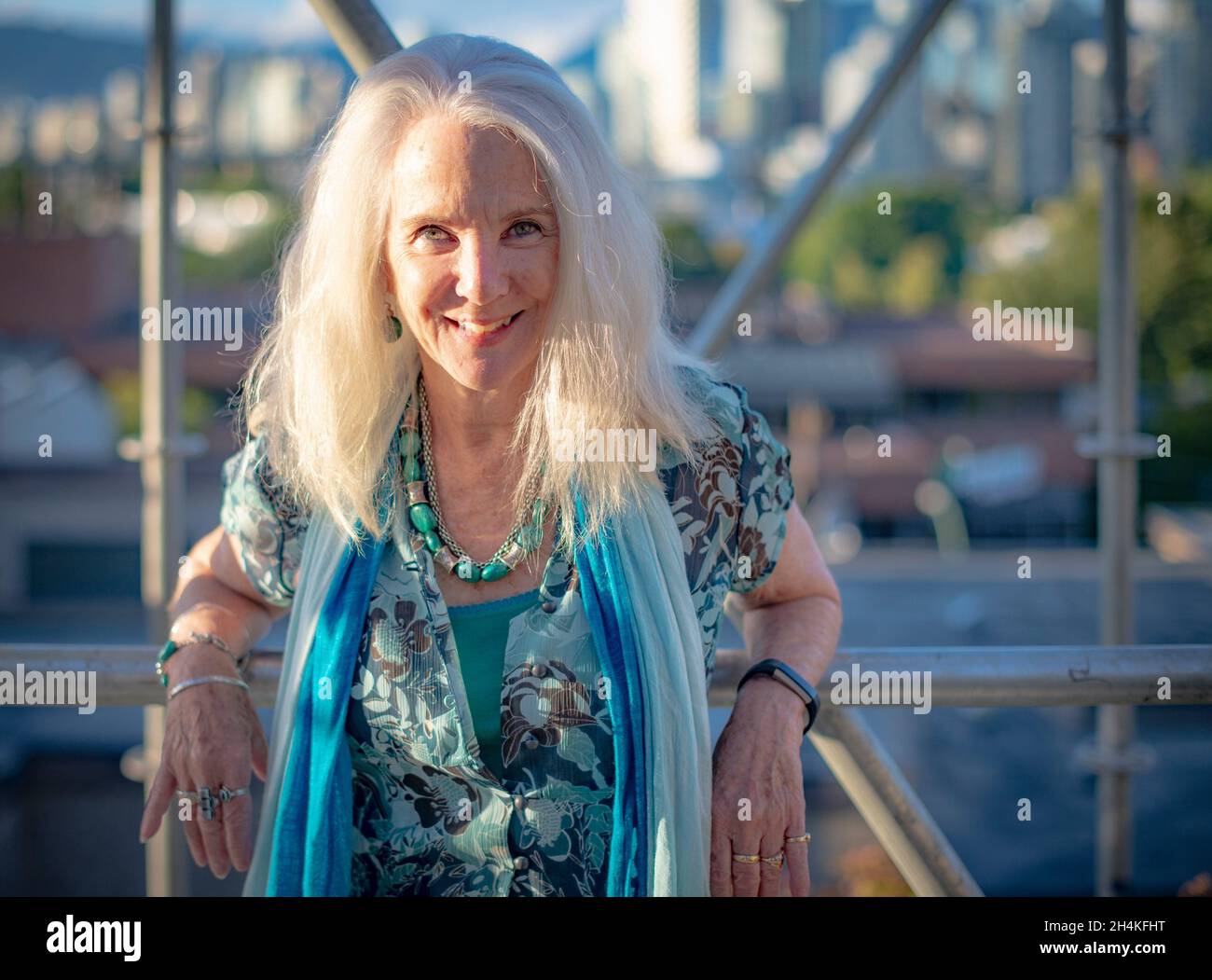 Una mujer, de 70 años, en un retrato en un andamio con vistas al centro de Vancouver, BC, Canadá. Foto de stock