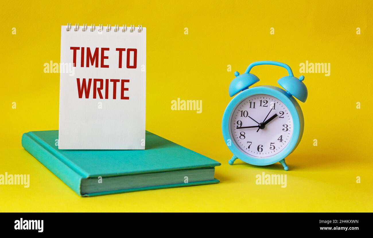 Texto para escribir palabras Tiempo para escribir, el texto se escribe en  bloc de notas y fondo amarillo. Reloj despertador cercano y bloc de notas  verde. Concepto de negocio para urg Fotografía