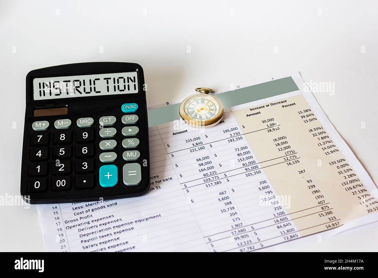 En la pantalla de la calculadora, la palabra INSTRUCCIÓN. Sobre un fondo blanco documento financiero y reloj Foto de stock
