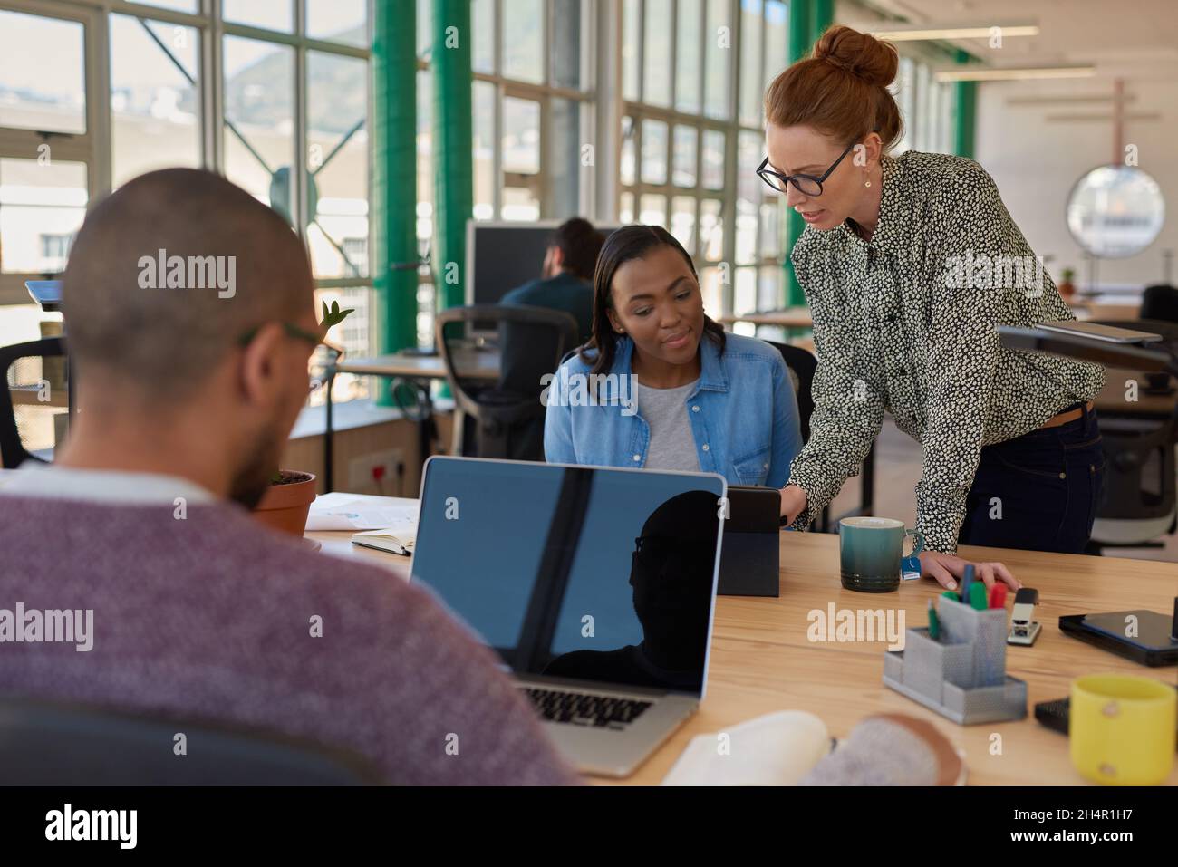 Dos empresarias diversas que trabajan en una tableta en una oficina Foto de stock
