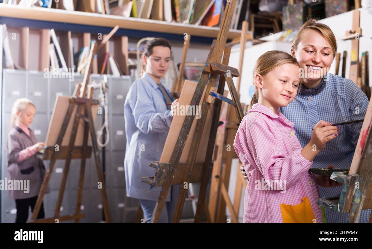 Mujer sonriente de asistencia chica durante la clase de pintura Foto de stock
