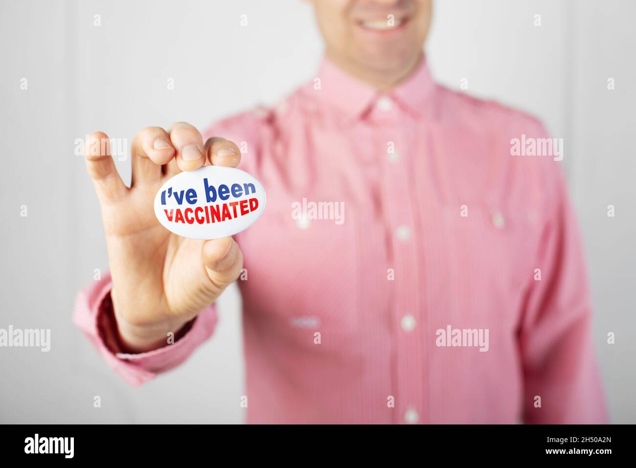 Alfiler de botón de campaña de vacunación en dedos machos caucásicos. He sido texto vacunado. Foto de stock