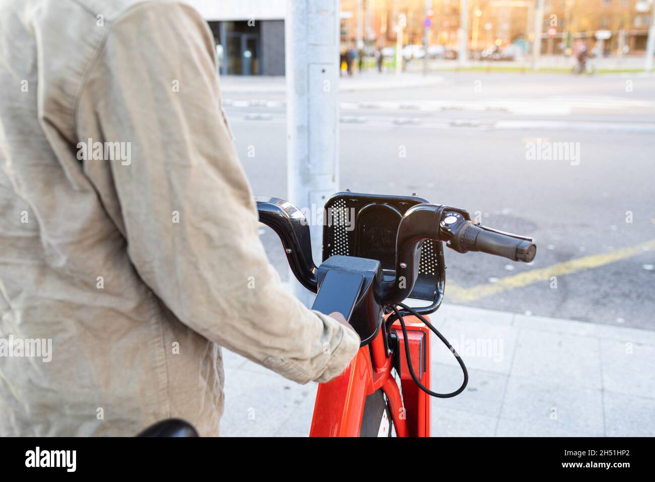 Persona irreconocible que toma una bicicleta en una plataforma de alquiler de bicicletas. Utilice su smartphone. Foto de stock