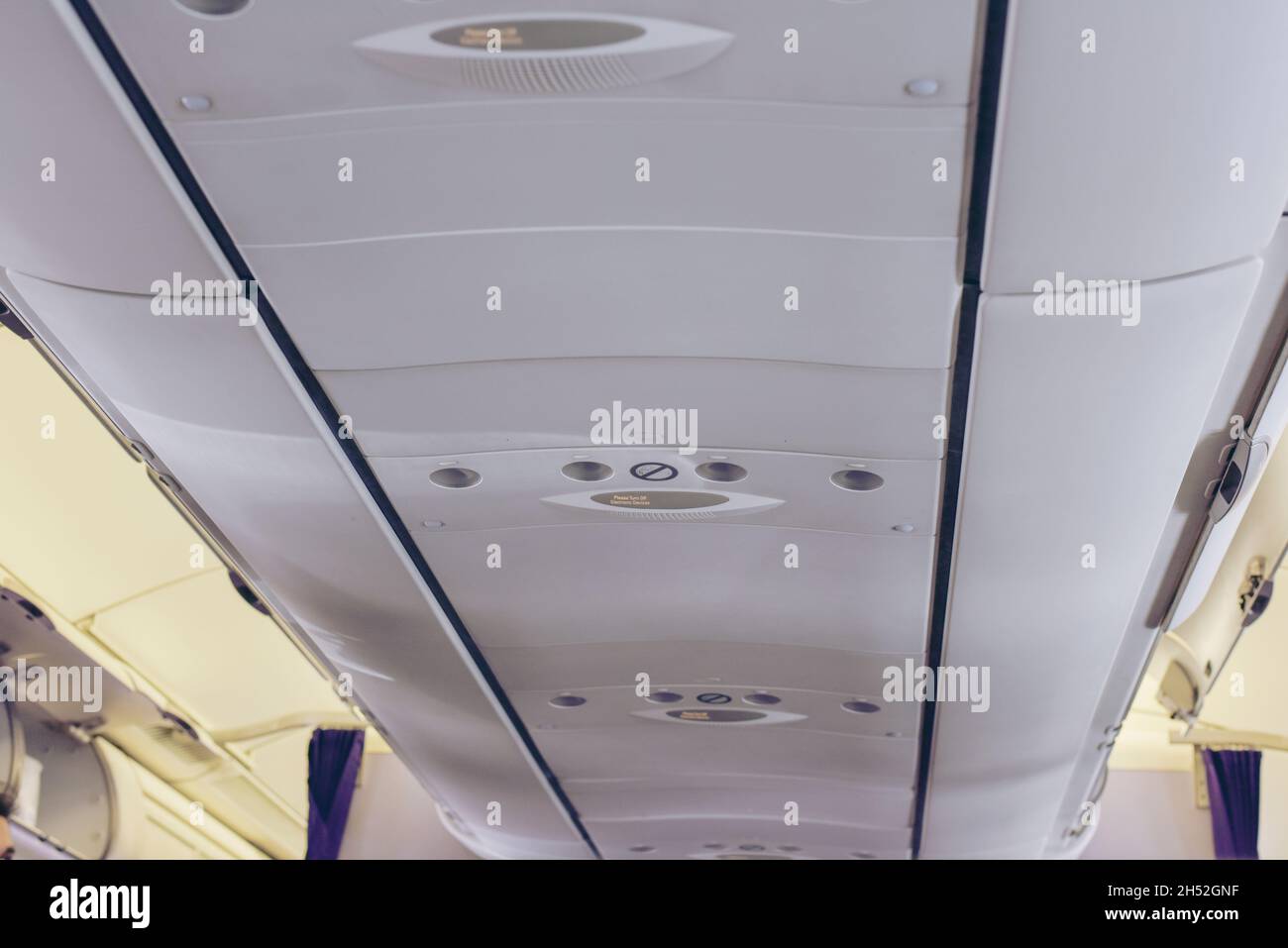 Cabina de Aviones Comerciales con Filas de Asientos en el pasillo.Interior del Avión con Pasajeros en Asientos.Equipaje de Carro en la Plataforma Superior sobre Cabezal Foto de stock