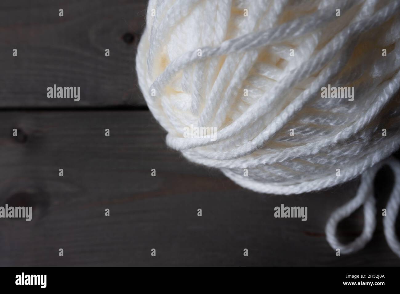 Bola blanca de lana sobre una mesa de madera. Foto de stock