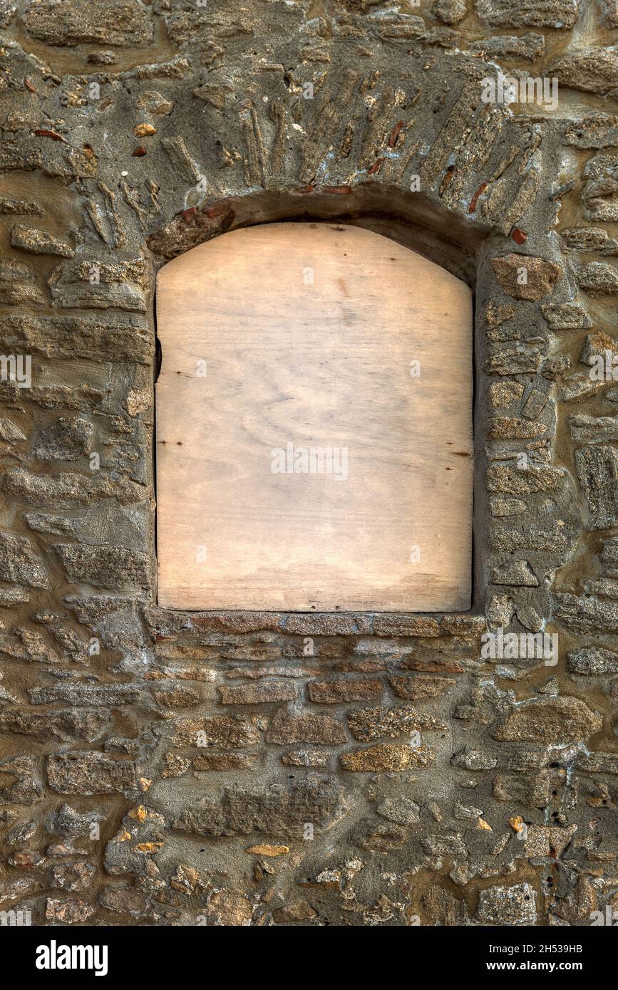 Ventana con una tabla de madera contrachapada con espacio para texto sobre una antigua pared de piedra, Grecia, 11 de octubre de 2021 Foto de stock