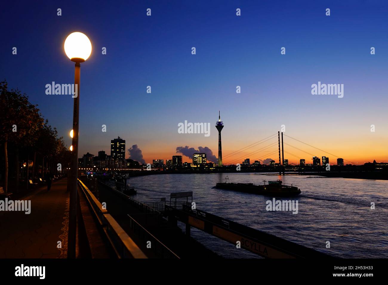 Moody escena nocturna del río Rin en Düsseldorf/Alemania con los dos puntos de referencia de la torre del Rin y Rheinkniebrücke. Foto de stock