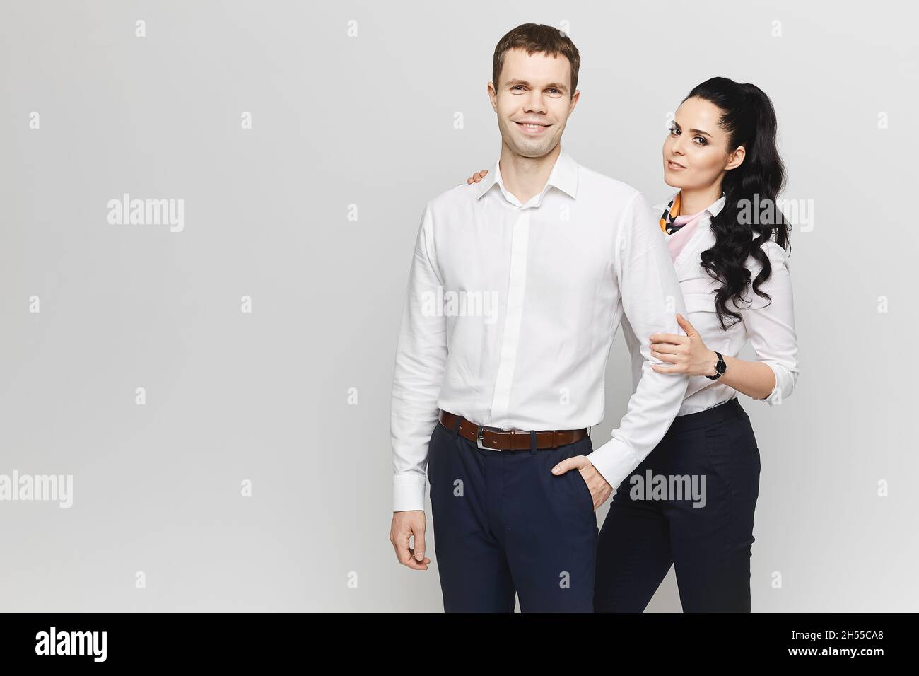 Desilusión añadir camino Una muchacha modelo bonita en la ropa de oficina de moda y un hombre guapo  joven en la ropa formal posan juntos en el fondo gris. Concepto de amistad  Fotografía de stock -