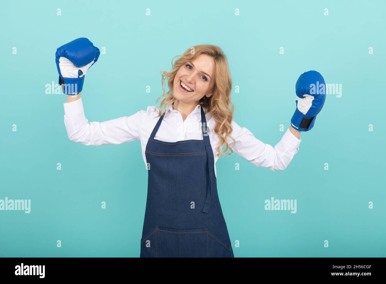 feliz mujer exitosa en delantal de cocina y guantes de boxeo, ama de casa Foto de stock