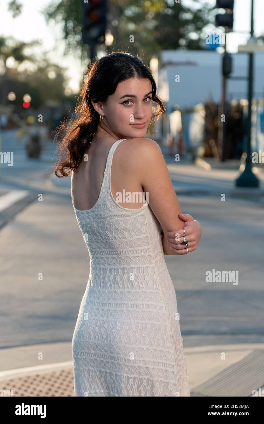 La muchacha mayor confiada de la High School secundaria mira detrás sobre su hombro con la luz del sol dorada que brillaba detrás de ella. Foto de stock