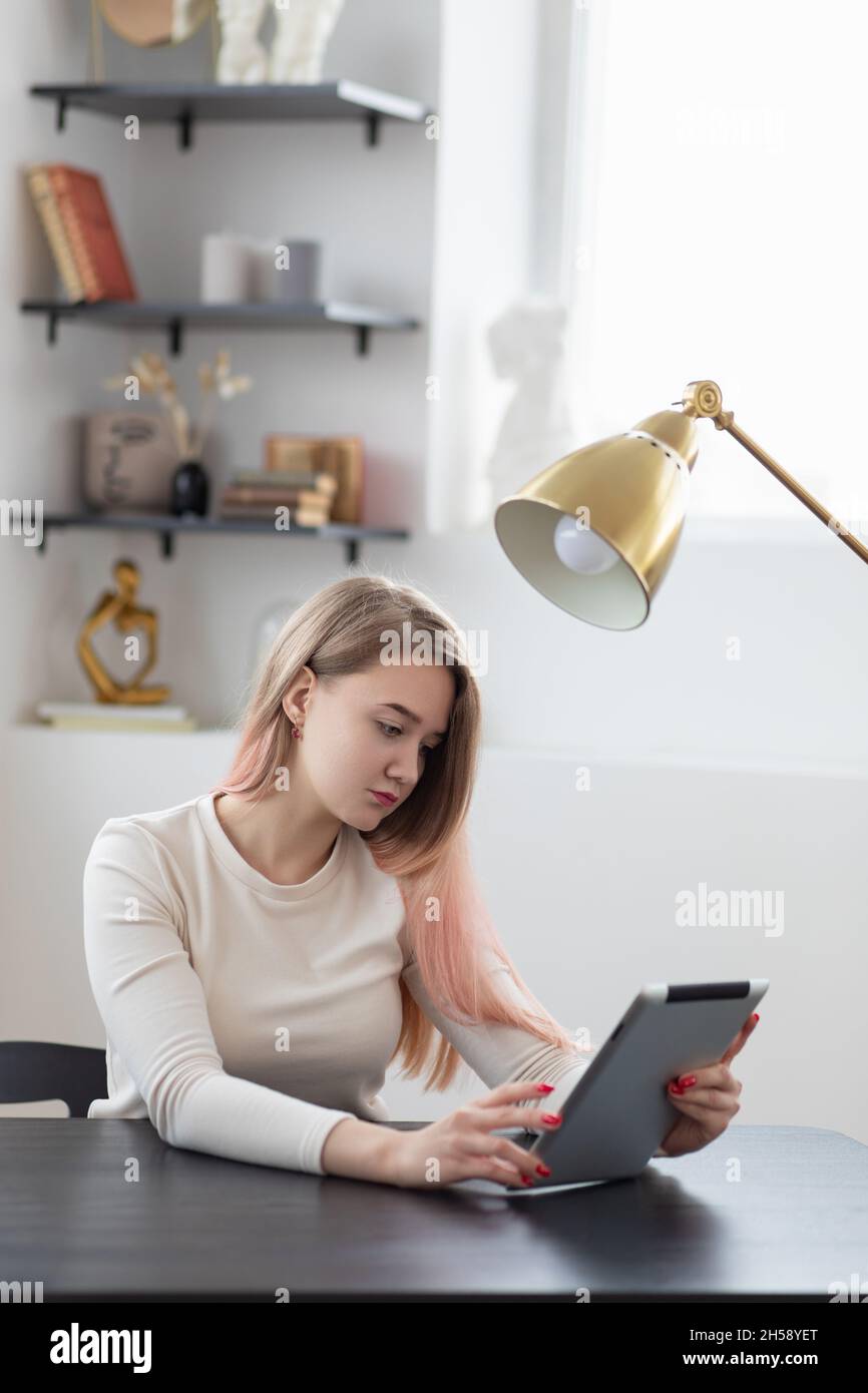 Concepto, mujer joven empresaria que trabaja y compra en línea en la oficina en tableta, tiro vertical. Foto de stock