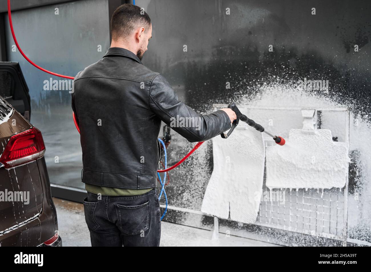 El hombre pone en el coche de espuma activa Mat. Lavado de coches. Complejo  de lavado de auto-servicio. Lavado de alta presión Fotografía de stock -  Alamy