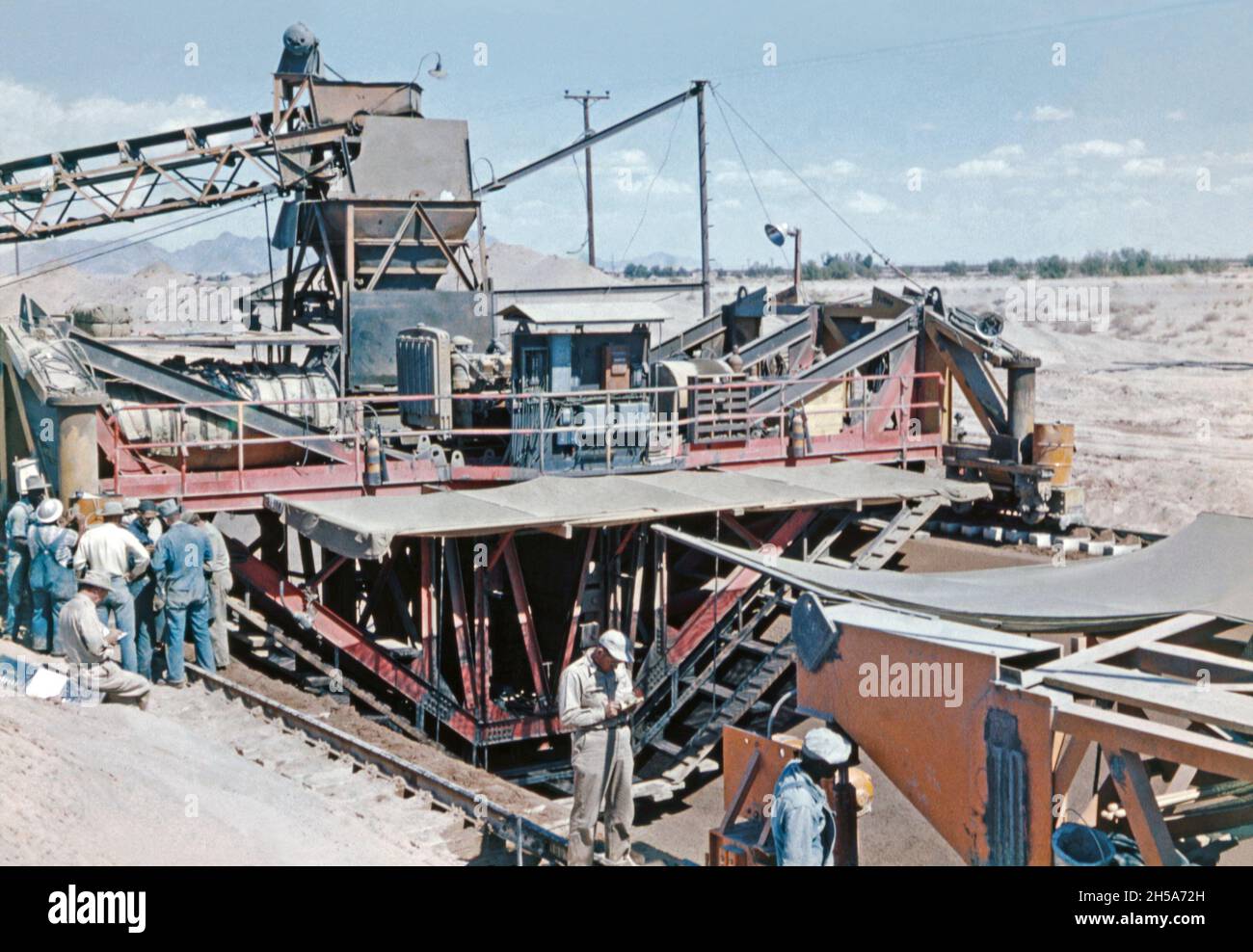 Trabajos de construcción en el canal Wellton-Mohawk, cerca de Yuma, Arizona, EE.UU. A principios de 1950s. Aquí los trabajadores están utilizando la máquina de revestimiento de canal, un dispositivo mecánico gigante en los rieles que pone hormigón, vertido desde la tolva en su parte superior, Que formará la base y los lados inclinados de la waterway.The Wellton-Mohawk Irrigation and Drainage District está ubicado en el suroeste de Arizona, al este de Yuma, construido entre 1949 y 1957. Permite el riego en el valle del Gila inferior con agua desde el río Colorado a través del Canal Gila hasta el Canal Wellton-Mohawk, donde se bombea alrededor de 160 pies. Foto de stock
