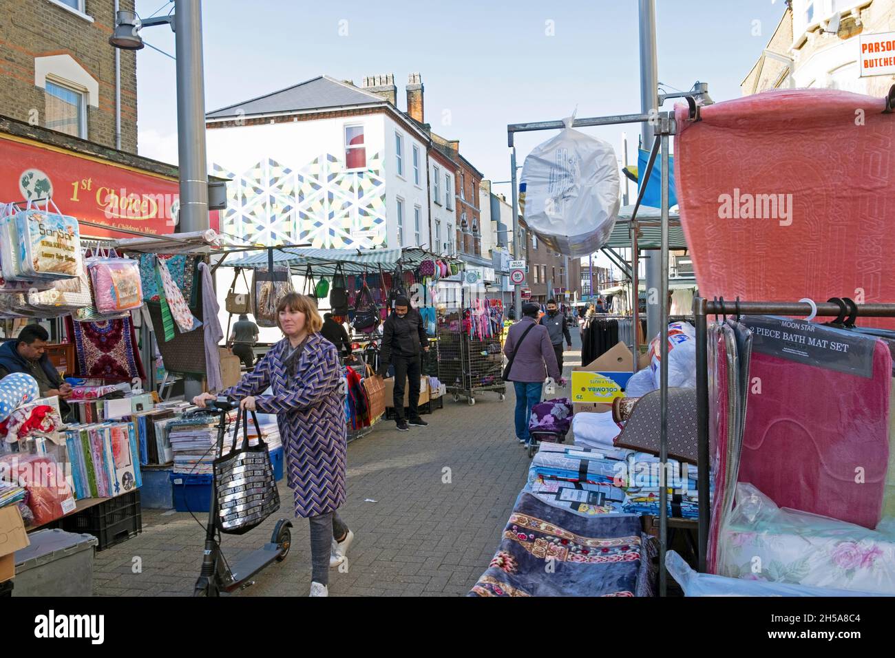Mujer empujando scooter más allá de puestos de mercado pocas personas caminando a lo largo de Walthamstow High Street los comerciantes de mercado en otoño de octubre de 2021 Londres Reino Unido KATHY DEWITT Foto de stock