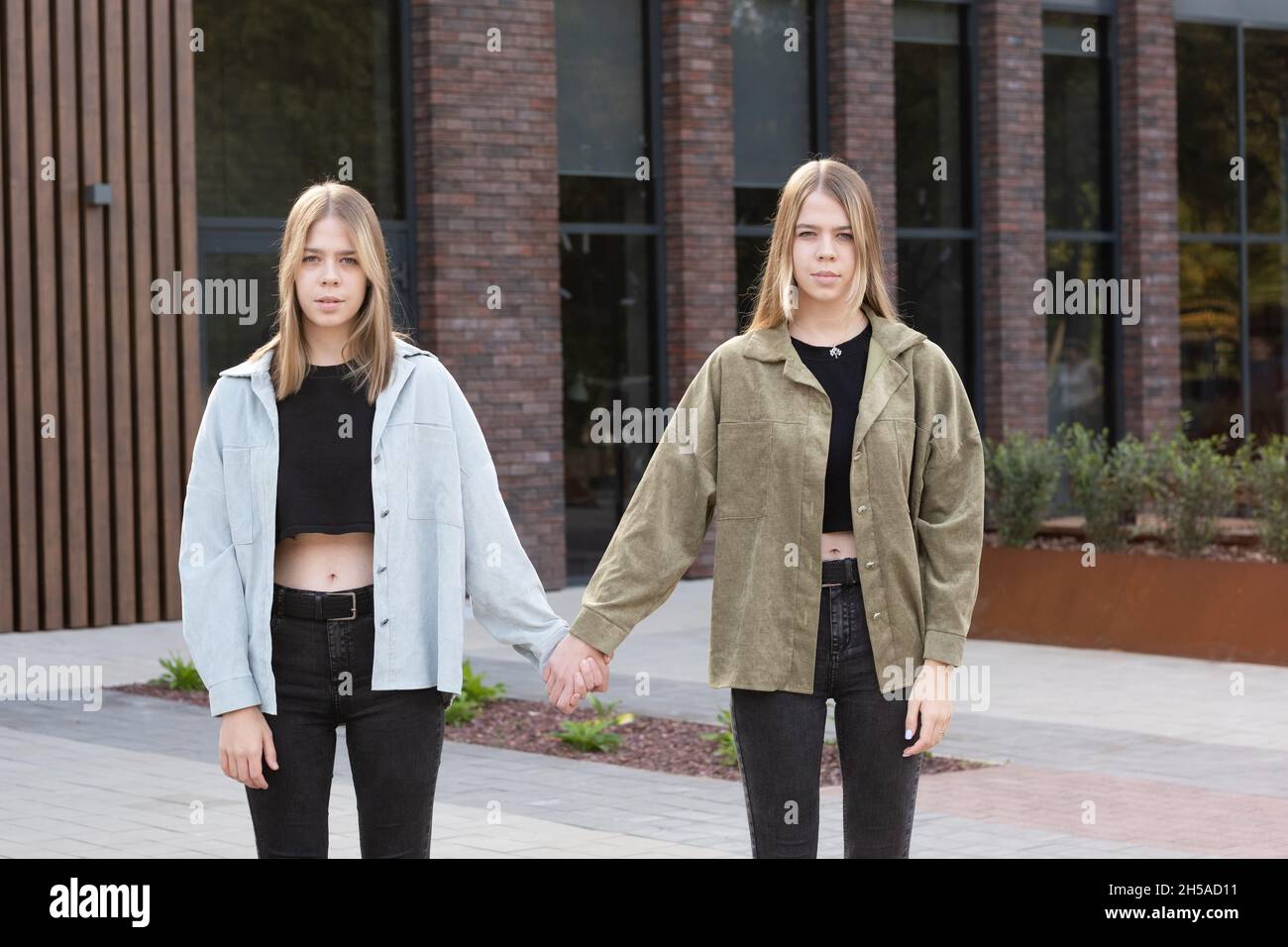 Tres comerciante seguro Las jóvenes y contemporáneas niñas gemelas en ropa de vestir con las manos  mientras se enfrentan a la construcción en el entorno urbano Fotografía de  stock - Alamy