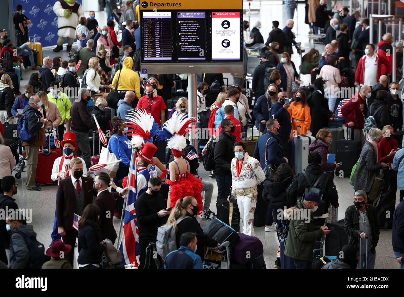 Los artistas intérpretes o ejecutantes se comprometen con los viajeros que  hacen cola para facturar en los vuelos de Virgin Atlantic y Delta Air Lines  en la terminal 3 del aeropuerto de
