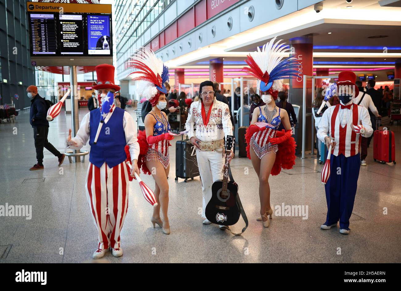Los artistas intérpretes o ejecutantes se comprometen con los viajeros que  hacen cola para facturar en los vuelos de Virgin Atlantic y Delta Air Lines  en la terminal 3 del aeropuerto de
