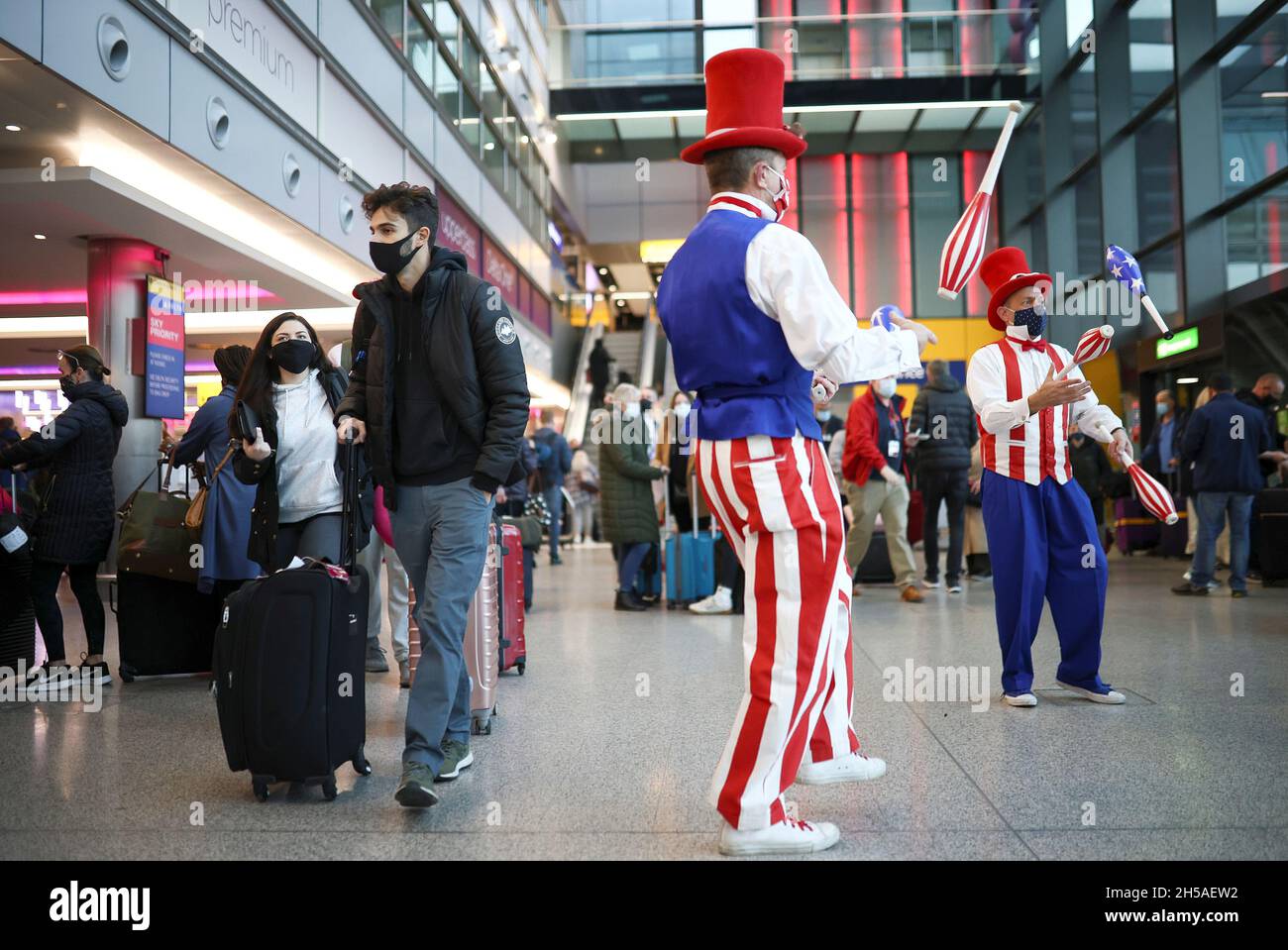 Los artistas intérpretes o ejecutantes se comprometen con los viajeros que  hacen cola para facturar en los vuelos de Virgin Atlantic y Delta Air Lines  en la terminal 3 del aeropuerto de