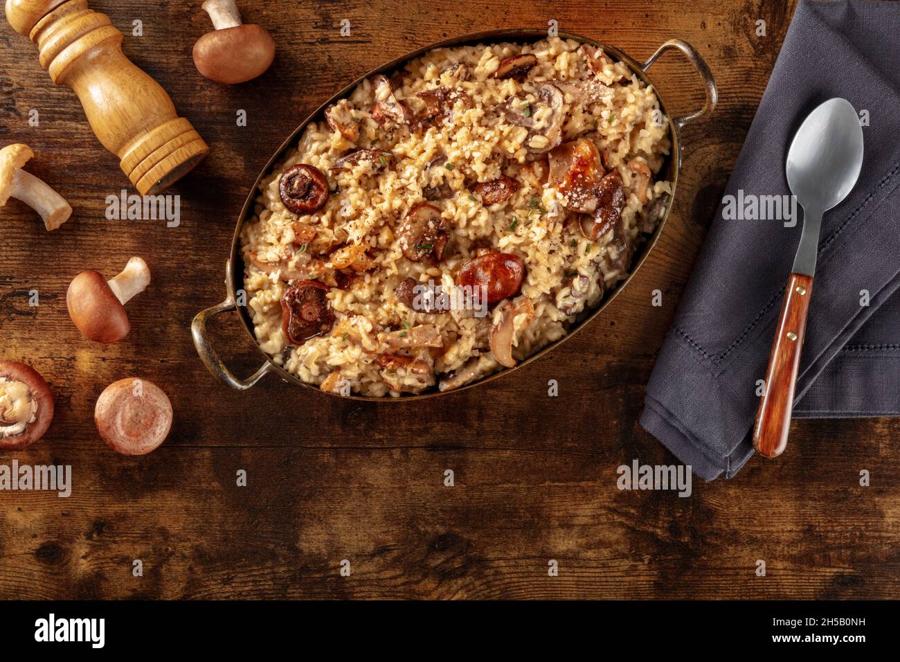 Risotto de setas, arroz rústico con varios champiñones, tumbado sobre un fondo de madera oscura con espacio de copia Foto de stock