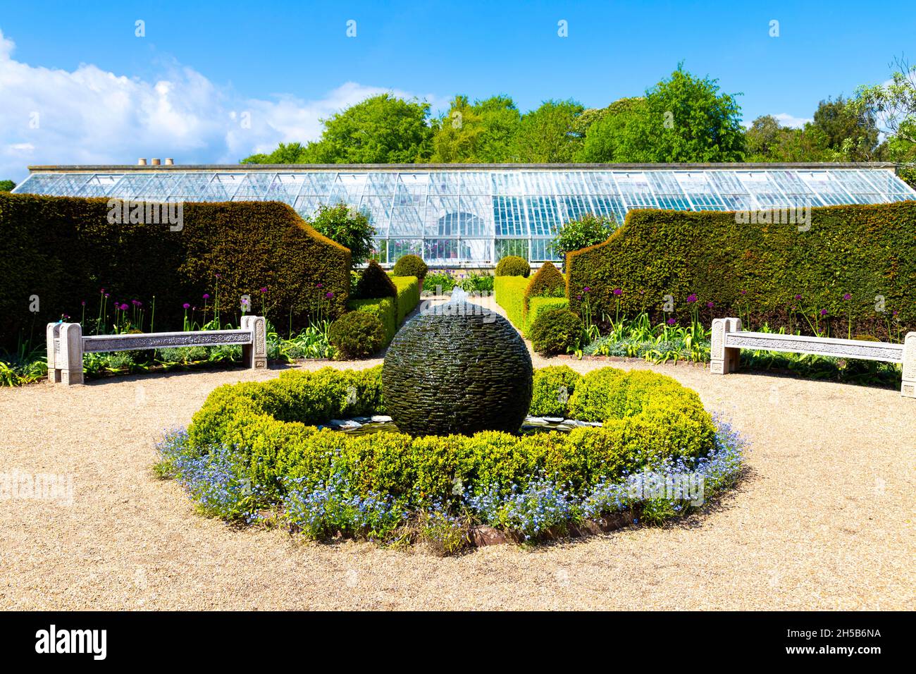 Fuente de escultura esférica y invernadero en la parte de atrás en el Jardín de las Flores, Castillo de Arundel, West Sussex, Reino Unido Foto de stock