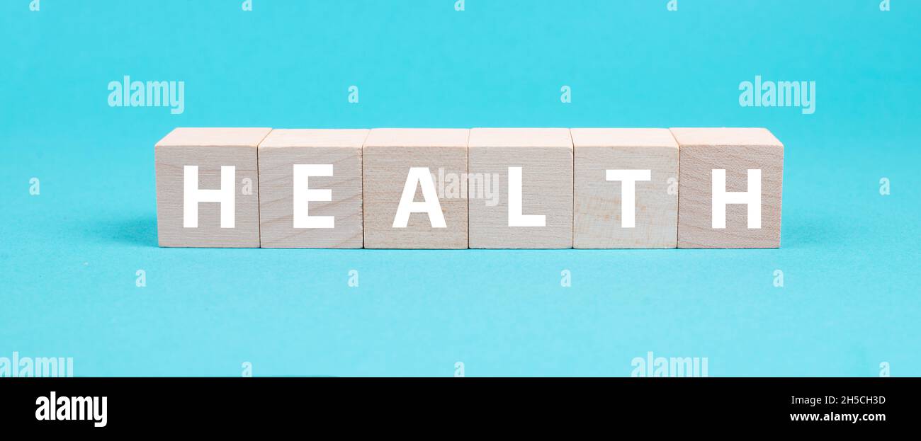 La palabra salud está de pie sobre cubos de madera, estilo de vida saludable, fondo azul Foto de stock