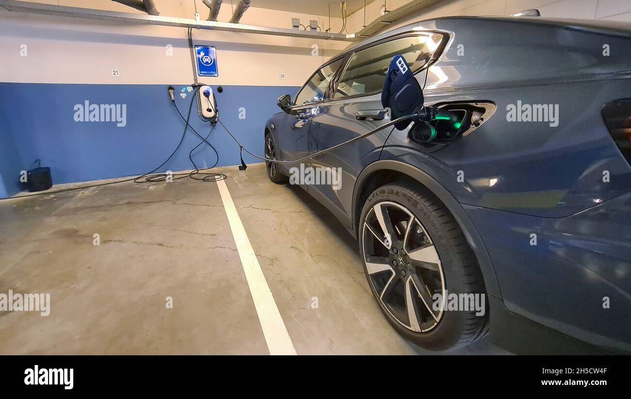 El coche eléctrico está cargado en un aparcamiento subterráneo Foto de stock