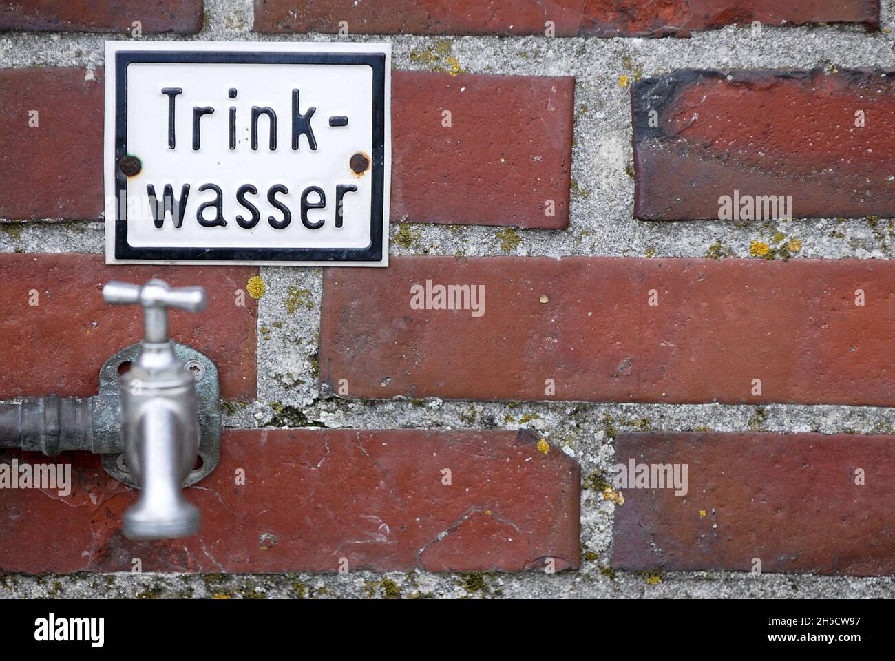 Grifo de agua en una pared con letrero Trinkwasser, agua potable, Alemania Foto de stock