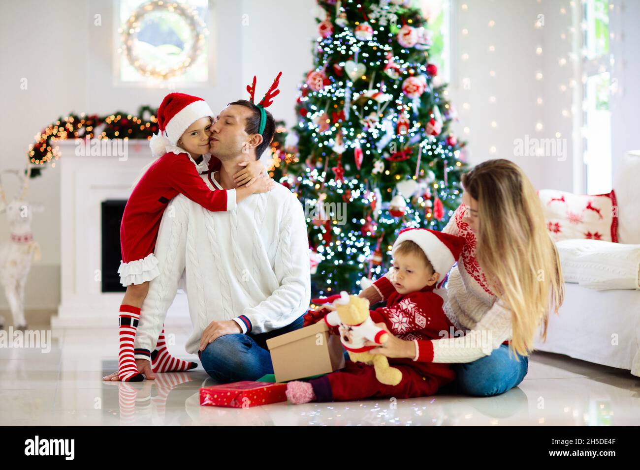 Familia celebrando la Navidad. Los padres y los niños decoran el árbol de  Navidad y los regalos abiertos. Niño con caja de regalo. Regalos de  apertura para niños. Decoración del hogar Fotografía