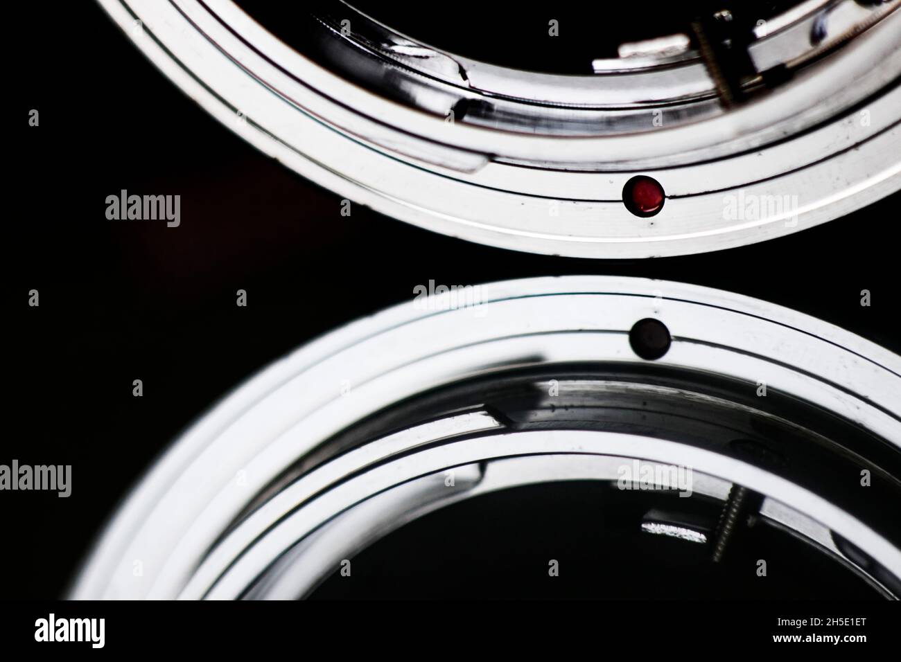 Fotografía macro del punto rojo de un adaptador de lente de cámara vintage de metal a SLR digital con reflejo. Foto de stock