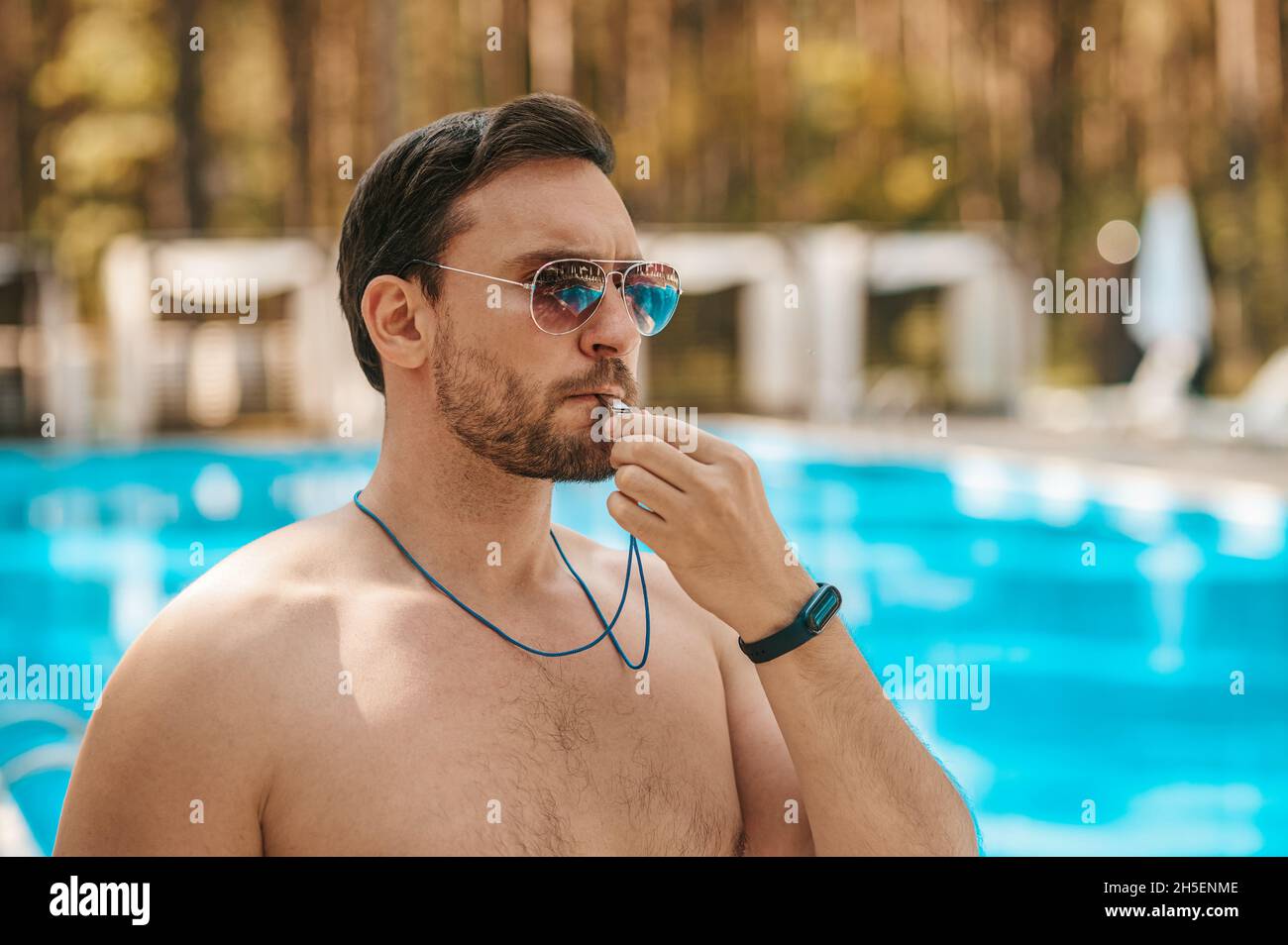 Hombre socorrista en gafas de sol cerca de la piscina pública