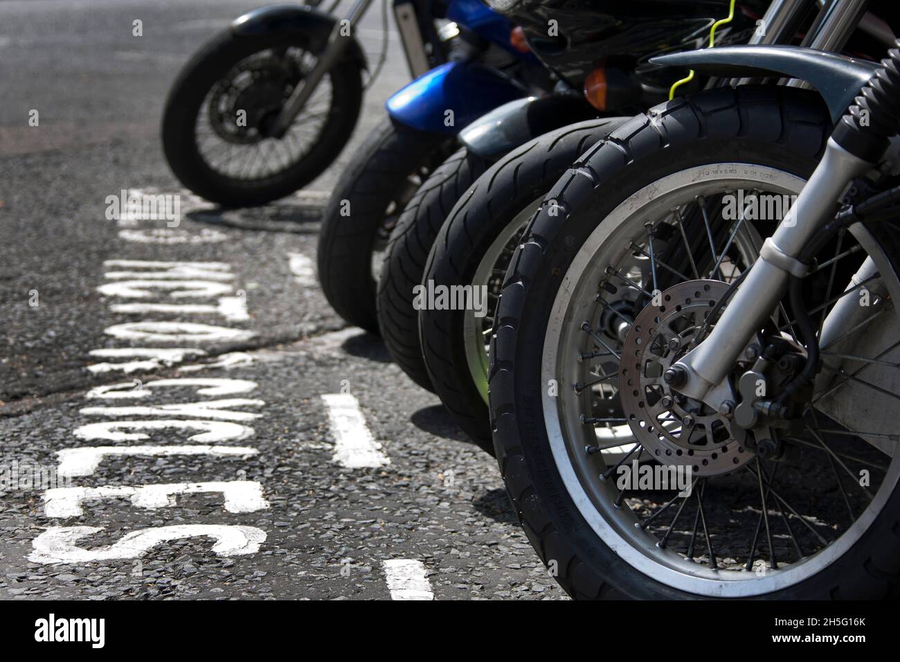 Ruedas delanteras de motocicletas estacionadas en una bahía Foto de stock