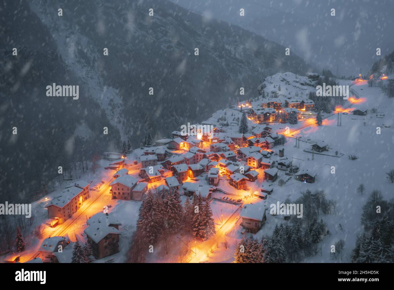 Nevadas invernales sobre cabañas tradicionales en el pueblo alpino de Pianazzo al atardecer, Madesimo, Valle Spluga, Lombardía, Italia Foto de stock