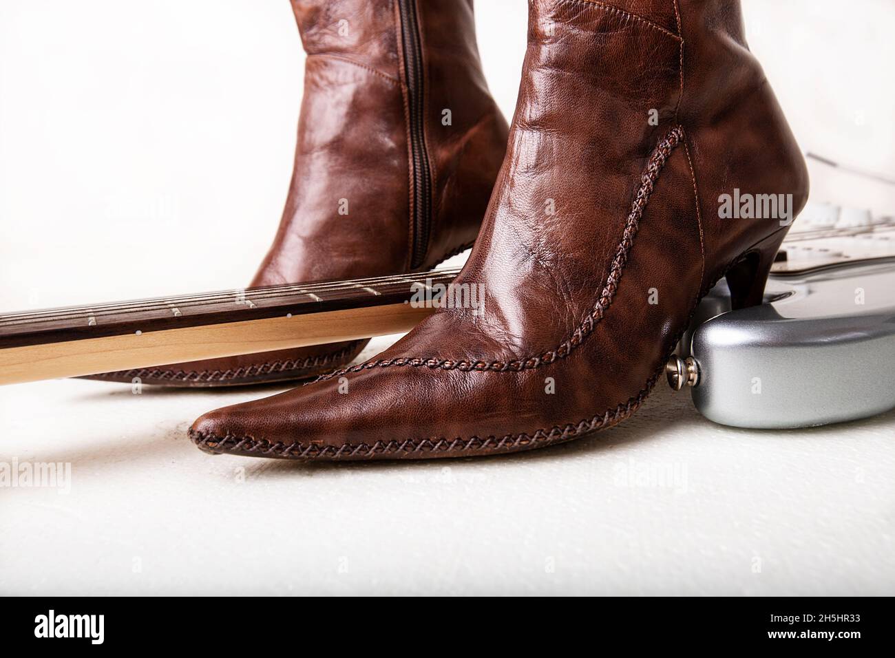 Guitarra eléctrica plateada y botas altas de tacones para mujer marrones  Fotografía de stock - Alamy