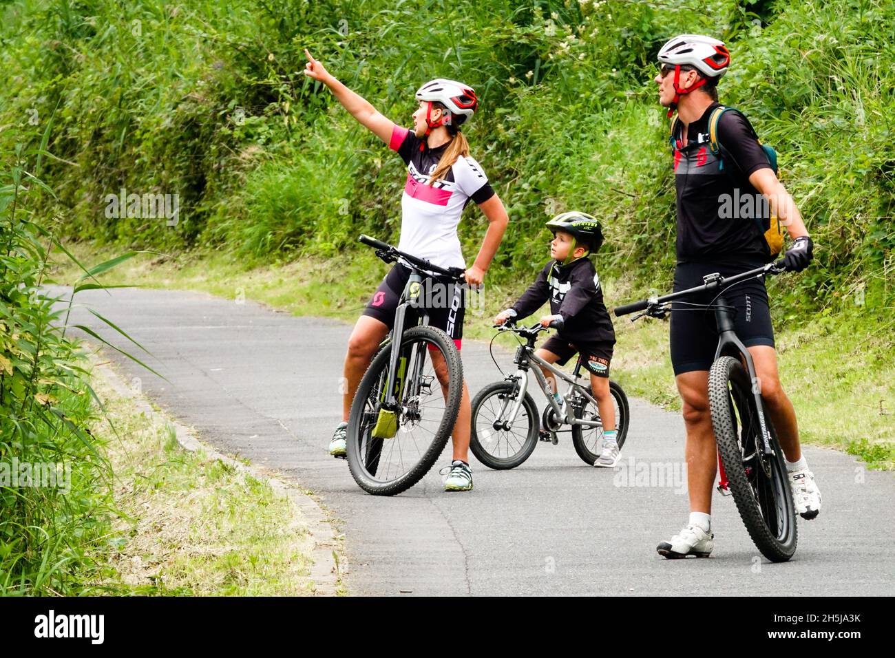Familia en bicicleta, padres y niño en un casco en la ruta de ciclismo Foto de stock