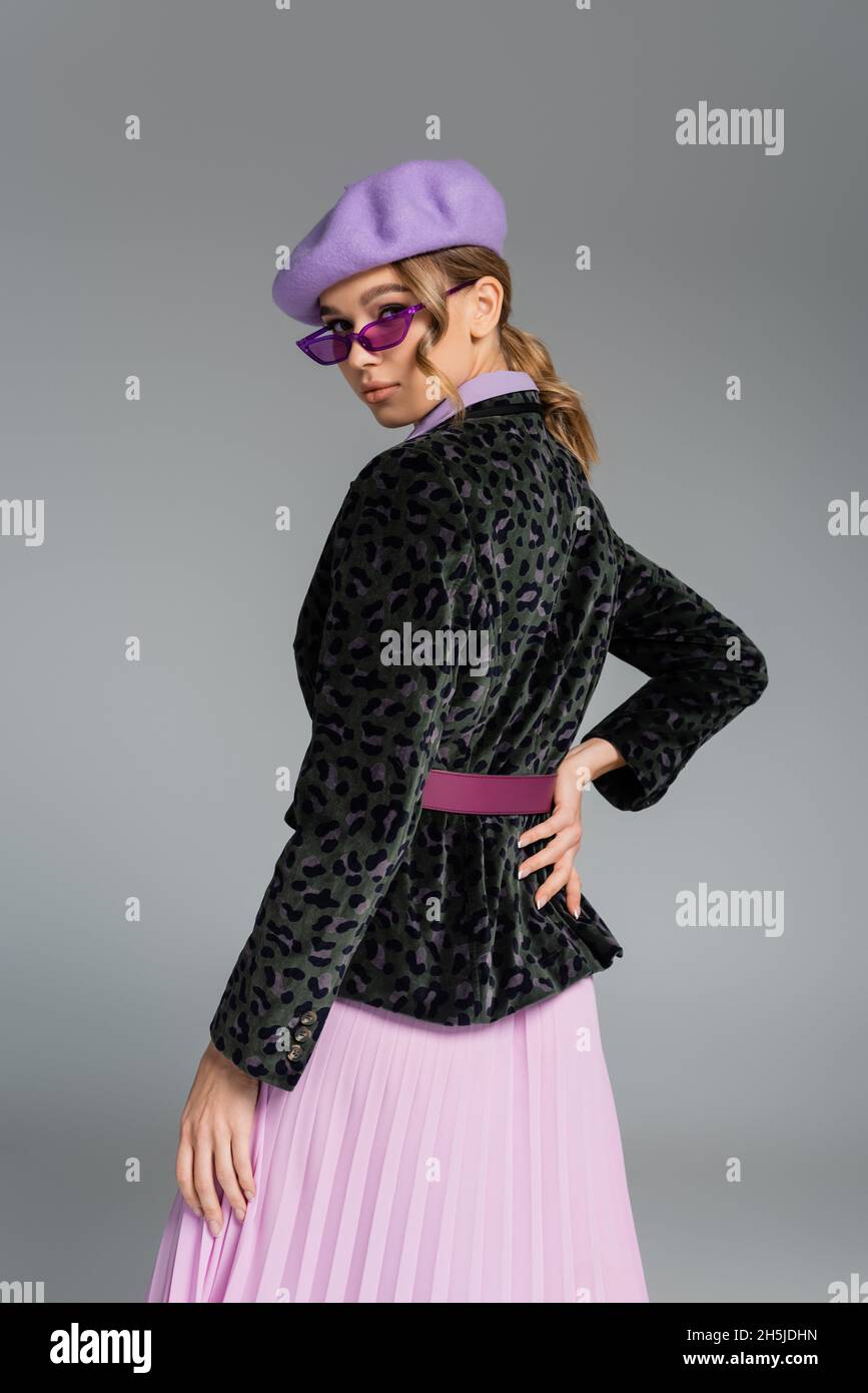 mujer joven de moda en beret y blazer con estampado animal posando con la  mano en la cadera aislado en gris Fotografía de stock - Alamy