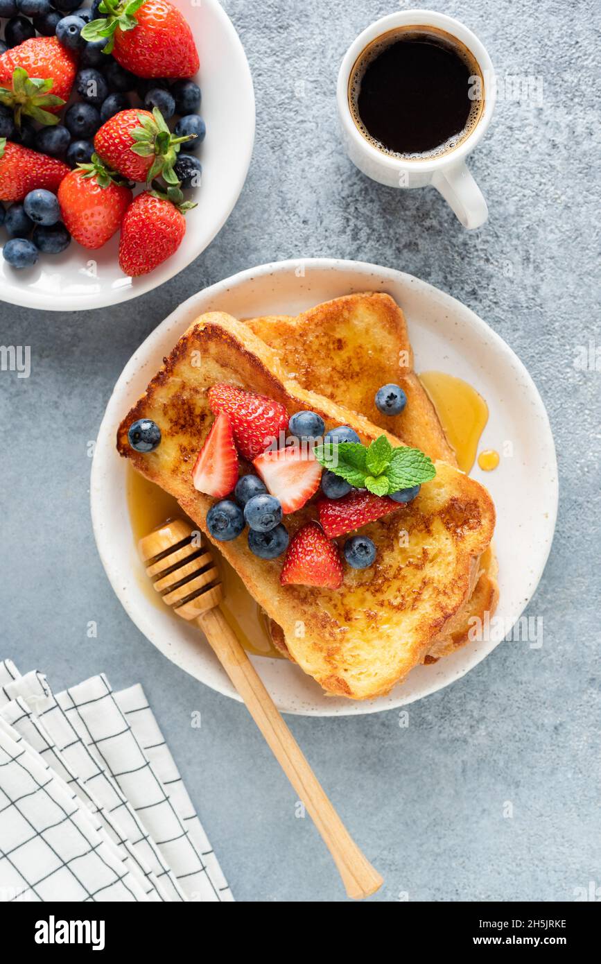 Tostadas francesas con bayas frescas y miel, servidas con una taza de café negro. Vista superior. Desayuno dulce Foto de stock