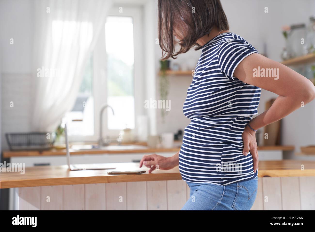 Vientre de una mujer embarazada que sostiene una mano bajo el